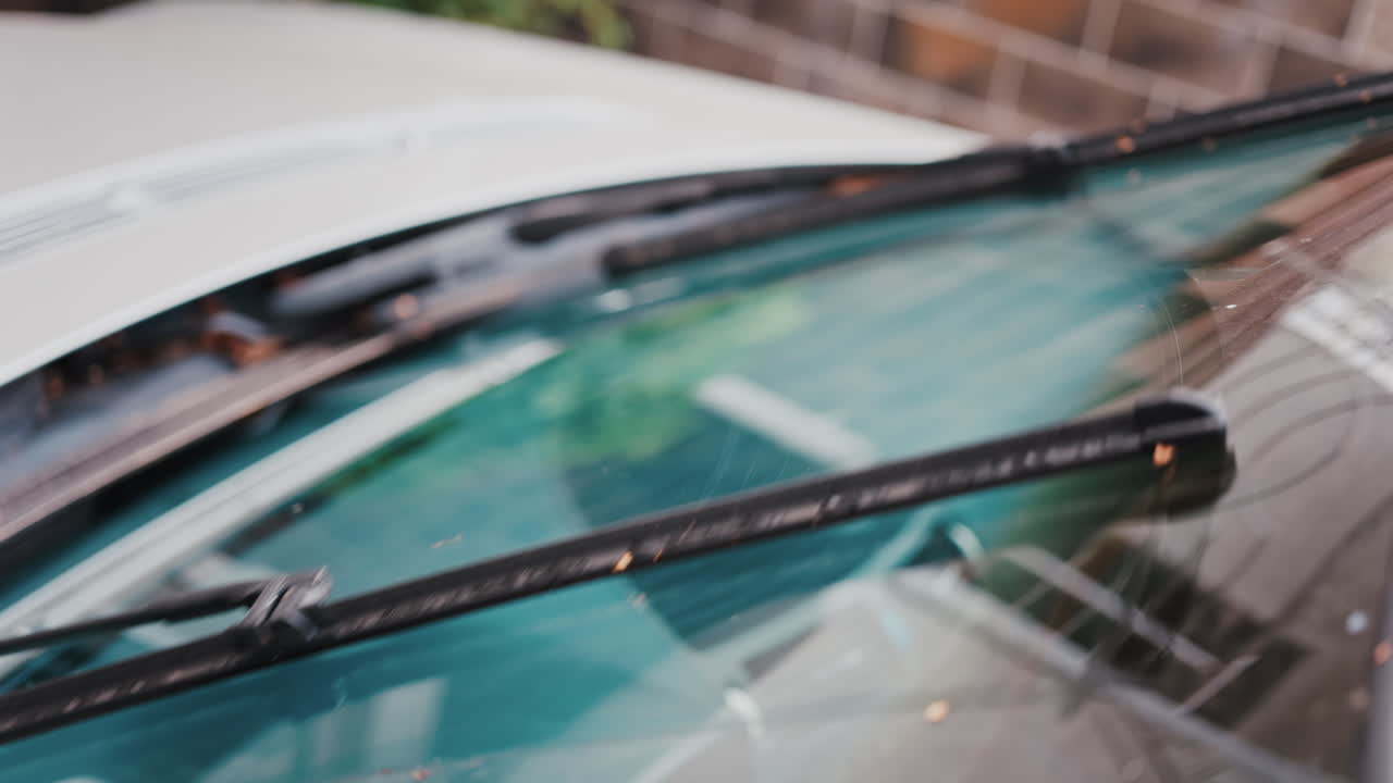 Close up of windshield wipers gliding across glass, reflecting clear visibility and care