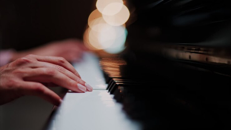 Close up of a woman's hands playing the piano with blurry lights on the background