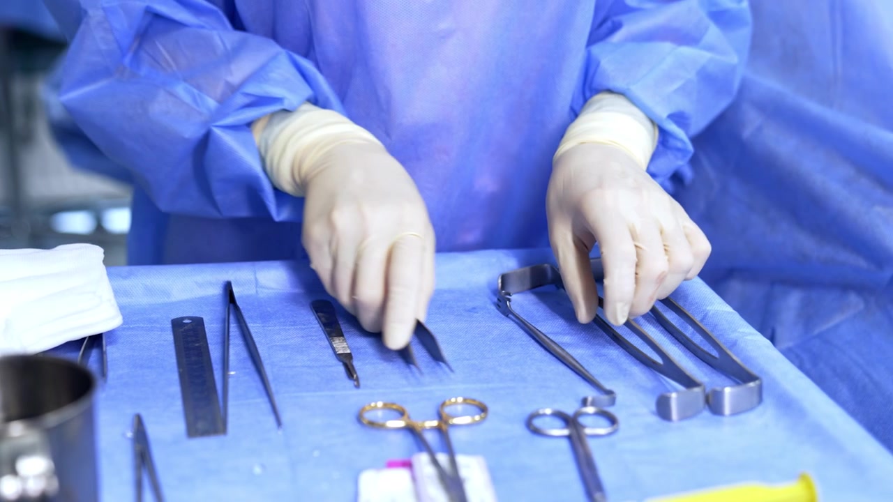 Enfermeira instrumentista não identificada organiza os instrumentos na mesa cirúrgica. Médico limpa os instrumentos para o doutor