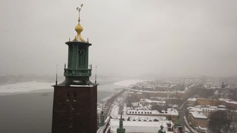 Smooth-rotating-aerial-footage-around-Stockholm-City-Hall-clock-tower-with-city-skyline-in-the-background