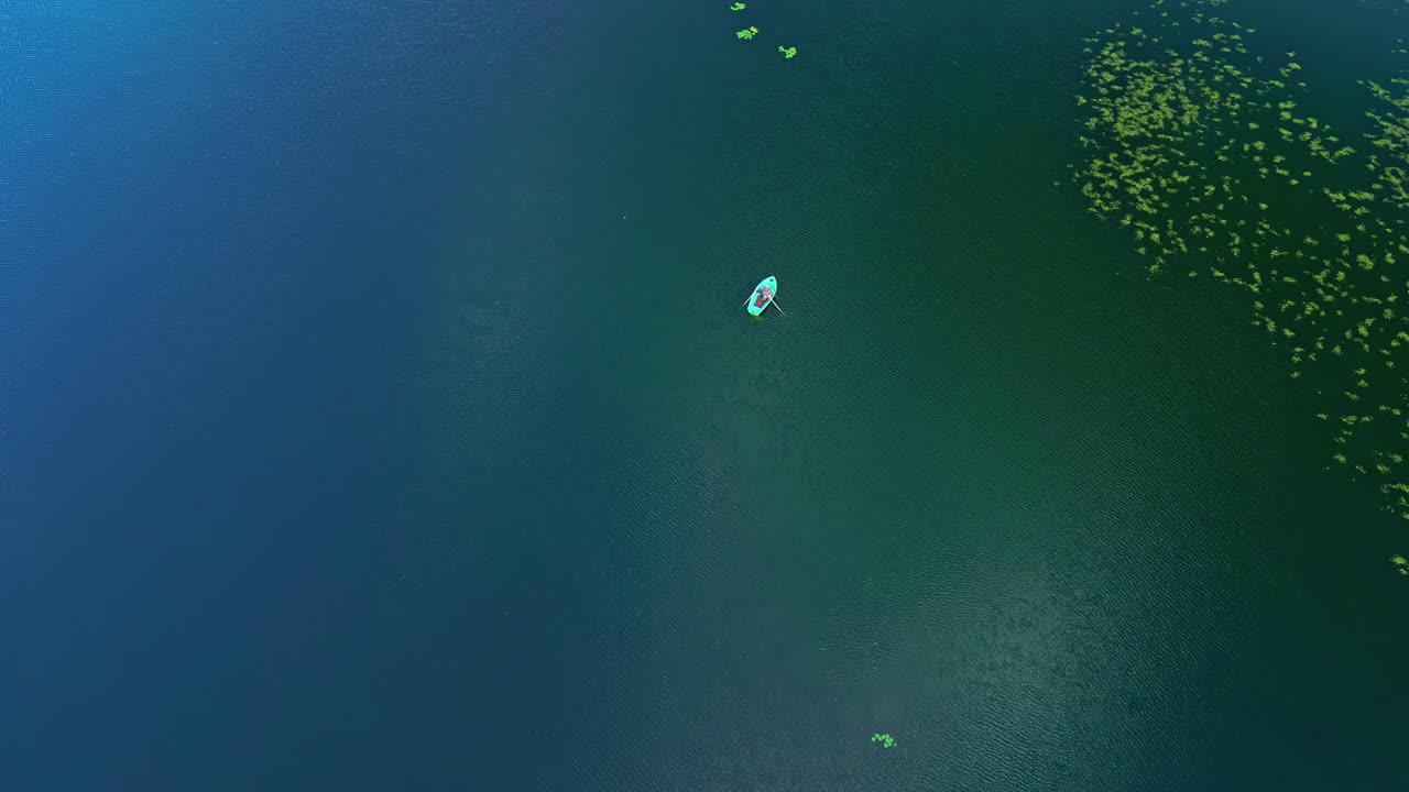 Tranquil Lake With A Person On Dinghy Boat Fishing During Daytime