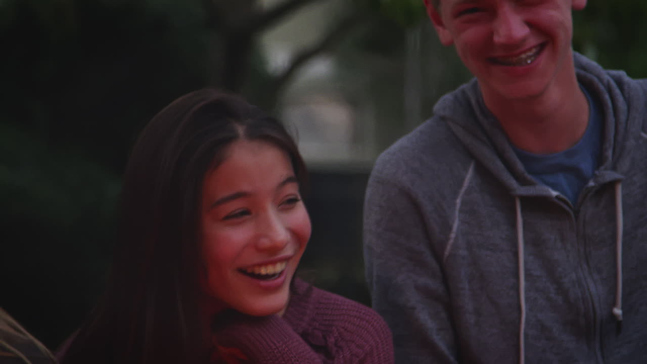 십대 친구 들 이 캠프 불 을 둘러싸고 웃고 있다