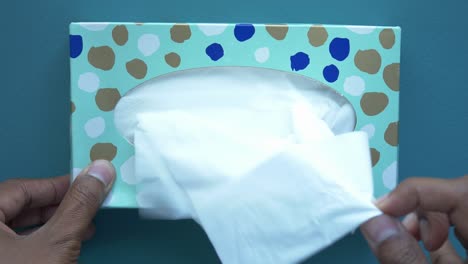 person taking tissue from a wall-mounted tissue box