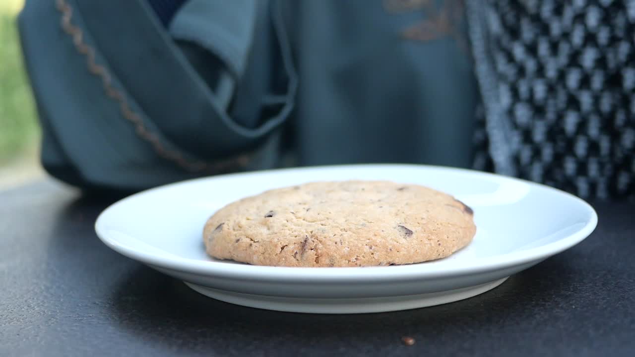 Woman eating a chocolate chip cookie outdoors