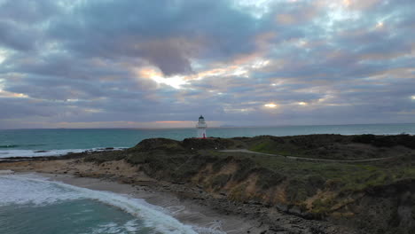 scenic aerial view flying toward a lighthouse along the rugged coast of the pacific ocean