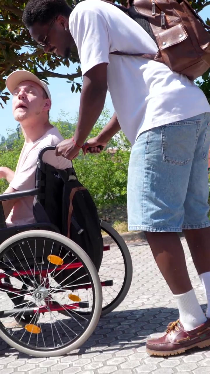 Ragazzo che spinge un amico in sedia a rotelle all'aperto