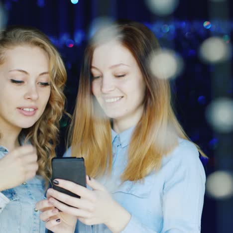 Two-Young-Women-Use-A-Smartphone-And-Have-A-Good-Time-1