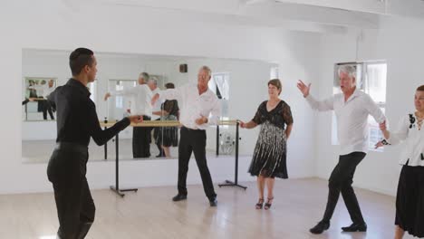 mixed race male dance teacher taking a ballroom dancing class at a dance studio