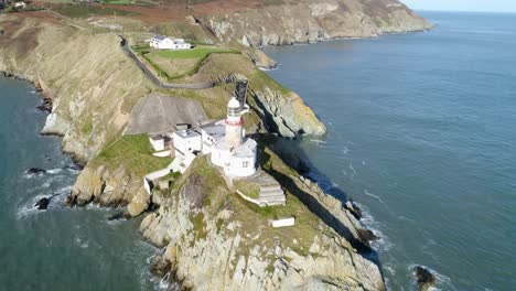 flying over the pier, the beautiful elements of the coast are on show such as the lighthouse, the colour varying grass and the colour transition of the littoral land in ireland