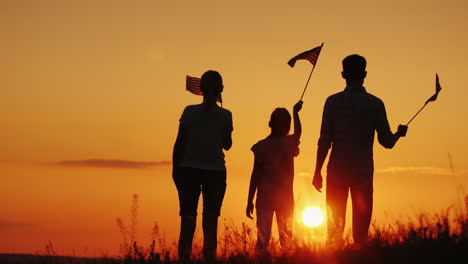 a family with american flags in their hands meets the dawn independence day celebration