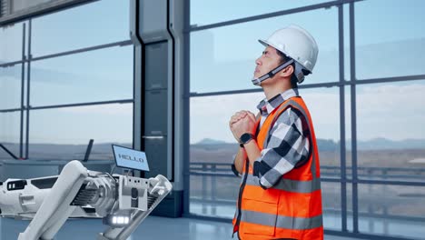 ingeniero orando cerca de un robot en una instalación moderna