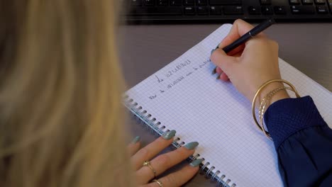 over the shoulder shot of a woman writing down information on a document