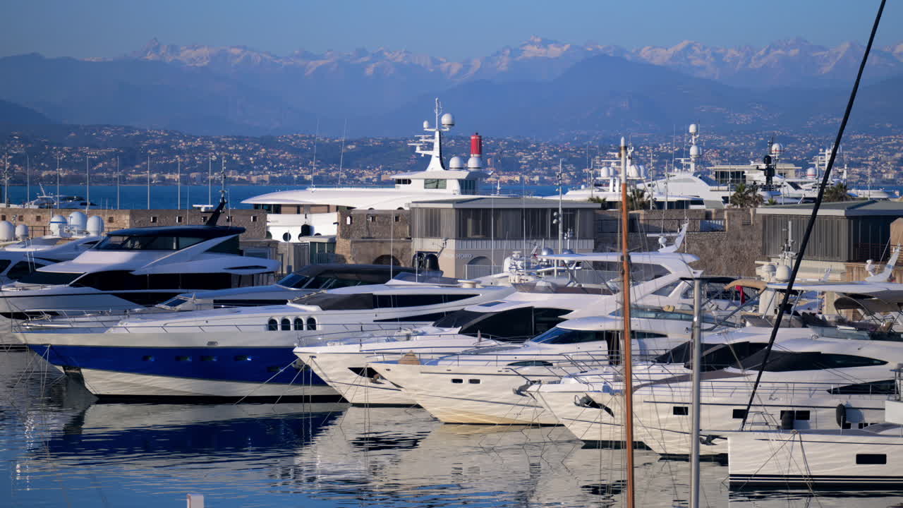 Cannes, France - March 3, 2025: Boats docked in the Cannes Marina with the mountains on the background