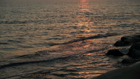 seawater waves are crashing on the beach at sunset