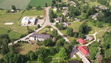 a drone view of brenguli village, capturing its quaint rural charm with scattered houses, lush green fields, and dense forests
