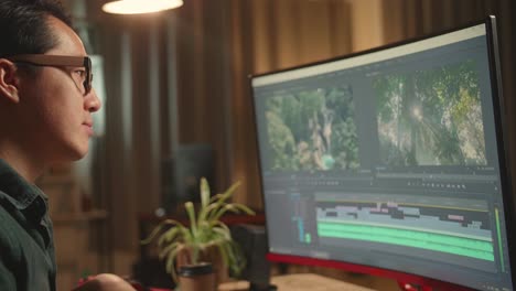 asian male video editor thinking while works with footage and sound on his personal computer, he works late at night