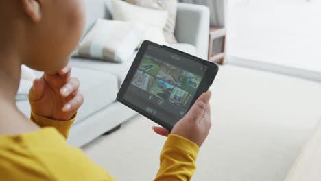 Happy-african-american-plus-size-woman-sitting-on-sofa,-using-tablet-in-living-room