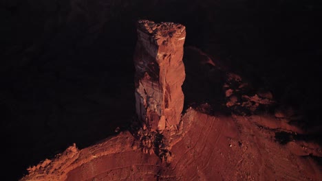 aerial tilt retreats from shadow behind golden castleton tower, sunset