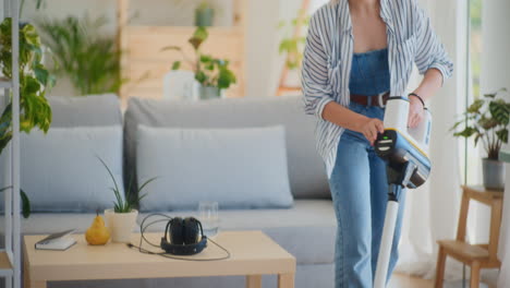 smiling woman vacuuming floor in house