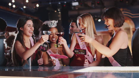 group of female friends celebrating with bride on hen party in bar