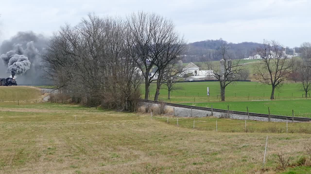 Experience the charm of a train journey through serene landscapes. Lush fields and trees frame the rails as the train moves, providing a tranquil backdrop of nature's beauty.