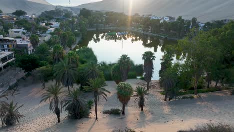 oasis del desierto huacachina, perú con lago y palmeras, con grandes dunas de arena en el fondo