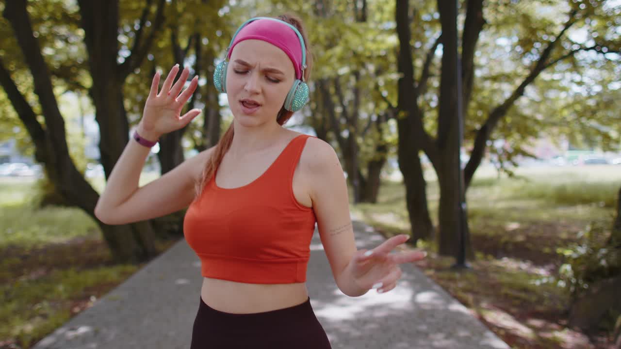 corredora deportiva chica bonita entrenamiento ejercicio escuchar música en auriculares bailar divirtiéndose en el parque