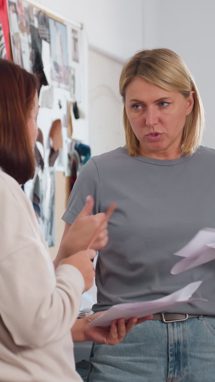 una administradora blanca dando feedback crítico a un compañero sobre las revisiones, gesto firme y expresión concentrada en una oficina tipo estudio, intercambio de hojas con un lápiz, ambiente tenso pero profesional