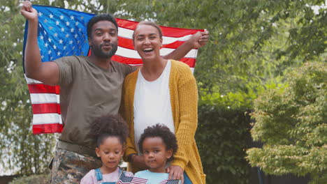 retrato de una familia del ejército estadounidense al aire libre en el jardín sosteniendo una bandera de estrellas y rayas