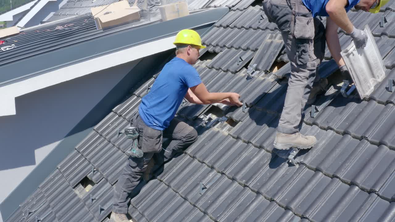 Two man placing tiles in a house roof. Renovation work. Medium shot
