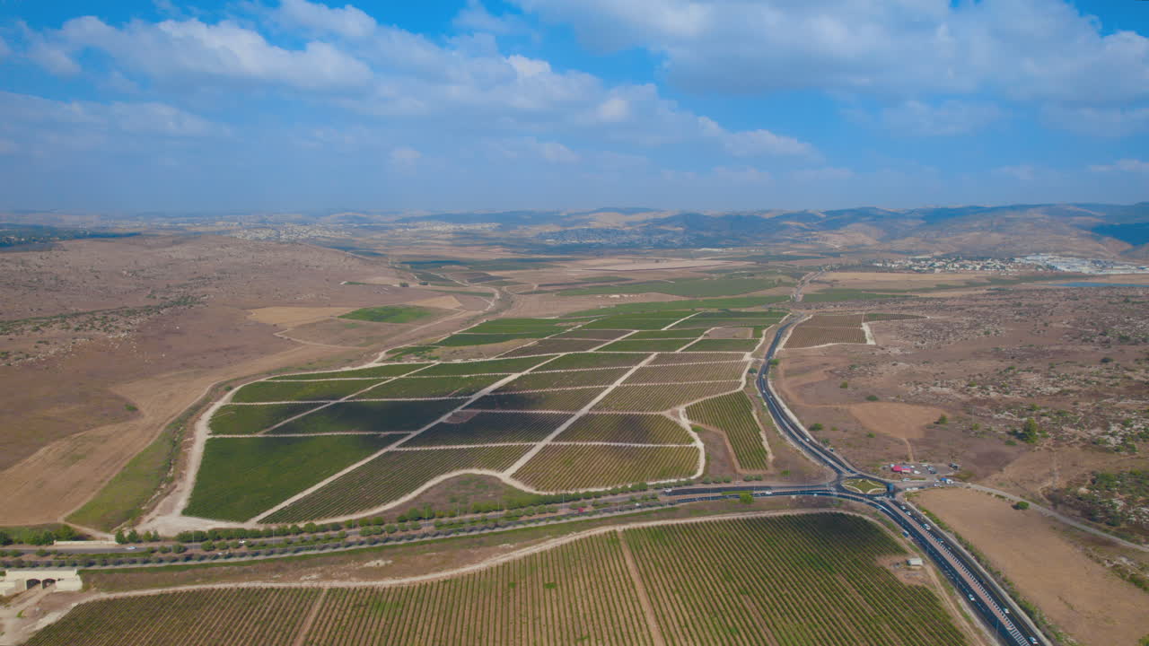 bella toma aérea de un valle con campos agrícolas y viñedos entre montañas y ciudades al fondo