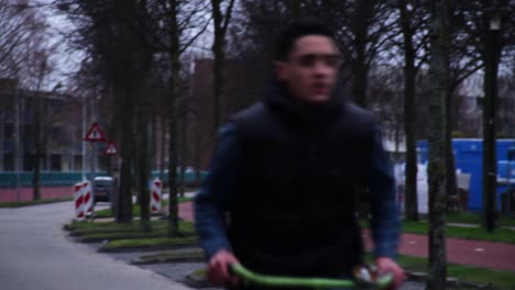 young middle eastern man cycling through a city in the netherlands