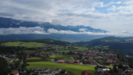 a picturesque aerial view of mutters, tyrol with mountain range and fields under a partly cloudy sky