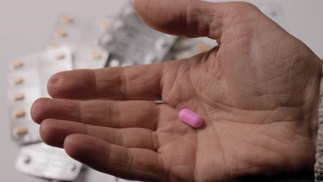 white pill in men's hand between fingers