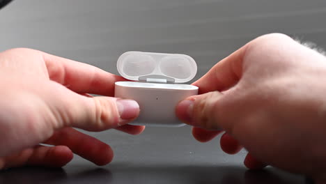 un joven usuario de auriculares gira en sus dedos una caja compacta blanca, fuente de entretenimiento y dopamina para escuchar música
