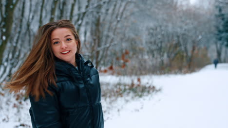 joyful caucasian woman jumping outdoors in winter. lady in black jacket turns around waving long hair.