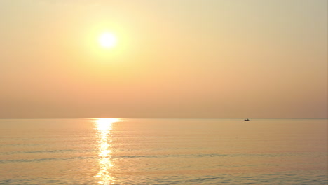 Puesta-De-Sol-De-Color-Dorado-Sobre-El-Océano-En-Calma-Con-Un-Barco-De-Pescadores-Lejos