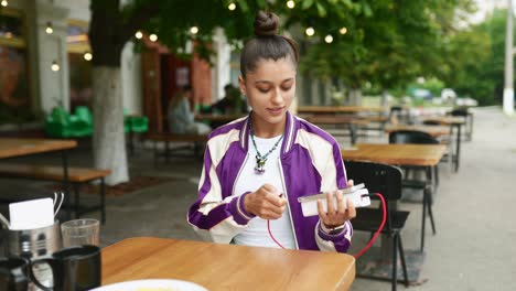 joven cargando el teléfono en un café al aire libre