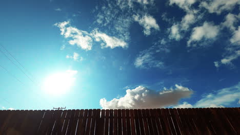 the view of clouds rolling over a wooden fence and power lines in the mojave desert, california - time lapse