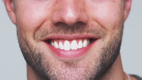 close up of mouth as man with perfect teeth smiles at camera in studio