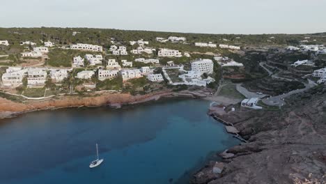 drone pushes over rocky cliff edge to cala morell at sunset