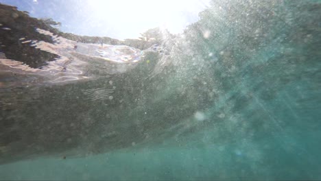 Vista-Submarina-En-Cámara-Lenta-Extrema-De-Una-Ola-Rompiente-En-La-Costa-Tomada-Desde-Debajo-De-La-Ola