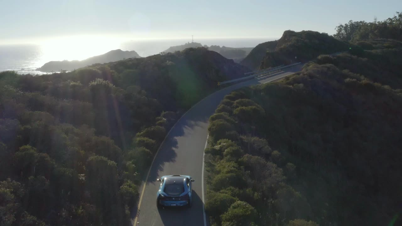 Riprese aeree, auto ibrida BMW i8 che guida su strada costiera a Marin Headlands, California