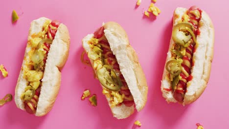 video de perritos calientes con mostaza, ketchup y jalapeno en una superficie rosa