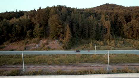 Aerial-shot-of-car-and-motorbike-driving-along-the-railway