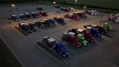 aerial view of numerous semi-trucks parked in a large lot at dusk
