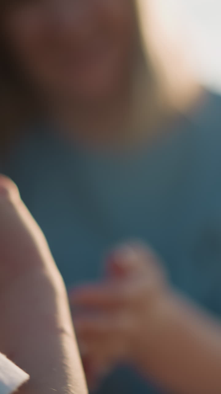 una toma ligeramente borrosa de un niño con una camisa blanca tomando una manzana roja de la mano de una mujer. el fondo es un entorno al aire libre, con la mujer también ligeramente fuera de foco, enfatizando la acción