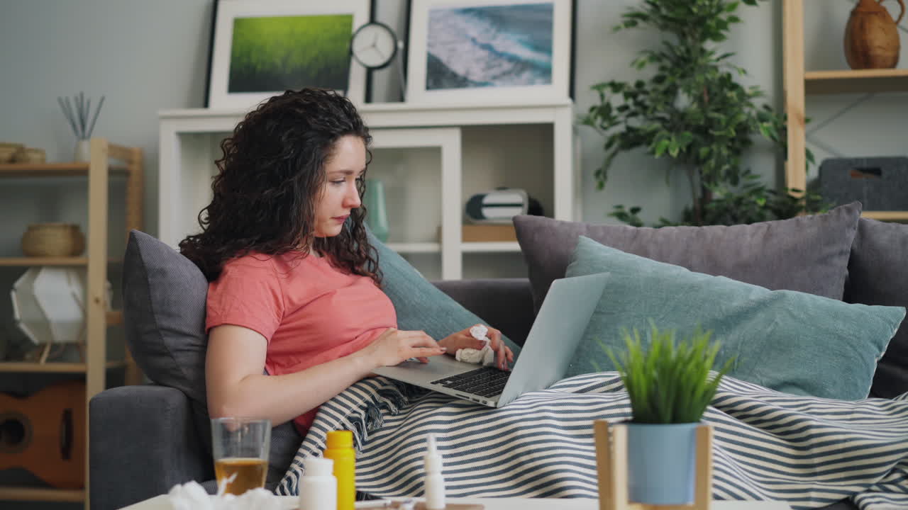 Woman Sick on Sofa Using Laptop
