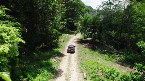 Forwards-tracking-of-offroad-car-slowly-driving-on-dust-road-in-forest-in-tropical-location