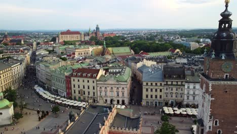 drone shot of town hall tower in main square of krakow old town with busy street and apartments
